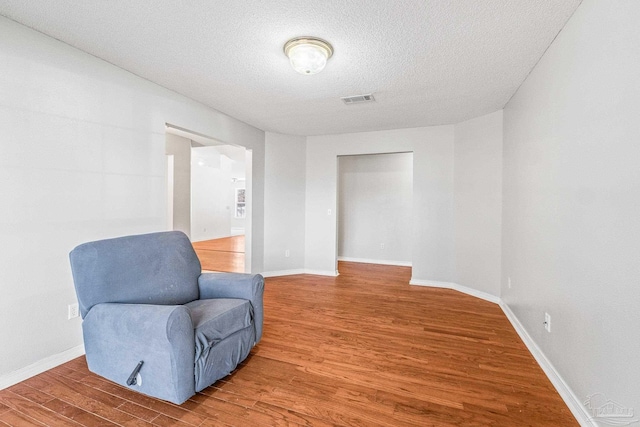 living area with hardwood / wood-style flooring and a textured ceiling