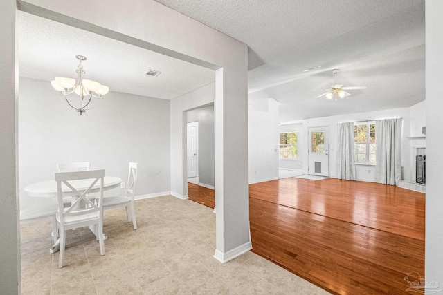 unfurnished dining area with a textured ceiling and ceiling fan with notable chandelier