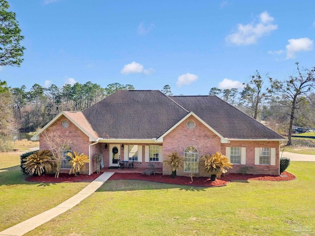 ranch-style house featuring a shingled roof, a front yard, and brick siding