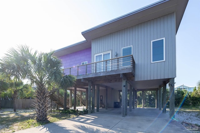 exterior space with a carport, driveway, fence, and a balcony