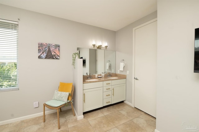 full bath featuring tile patterned flooring, a sink, baseboards, and double vanity