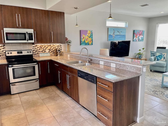 kitchen featuring tasteful backsplash, open floor plan, a peninsula, stainless steel appliances, and a sink