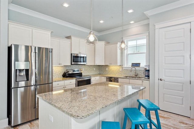 kitchen featuring ornamental molding, appliances with stainless steel finishes, a kitchen breakfast bar, and a center island