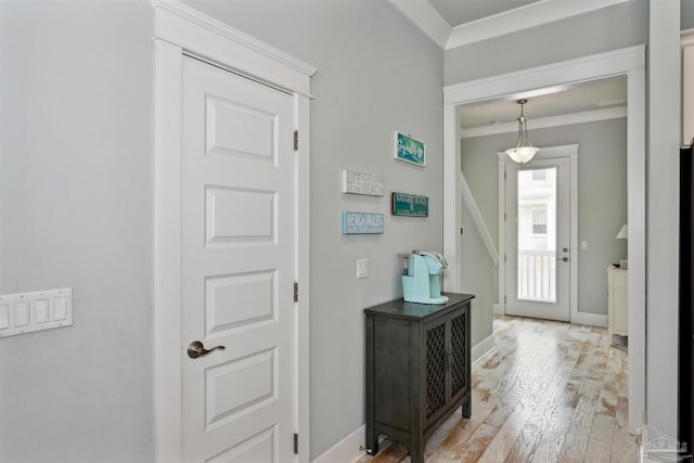 entryway with light hardwood / wood-style flooring and crown molding