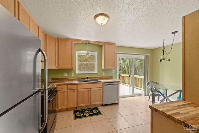 kitchen featuring appliances with stainless steel finishes, a textured ceiling, sink, light tile patterned floors, and hanging light fixtures