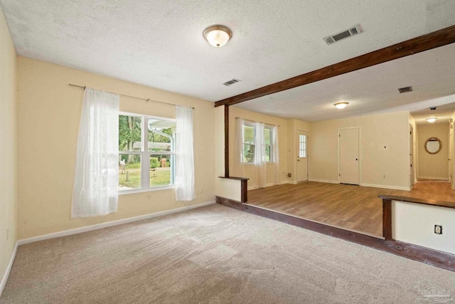 unfurnished living room with beam ceiling, a textured ceiling, and hardwood / wood-style flooring