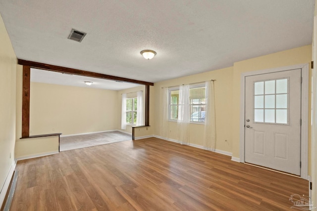 foyer with beam ceiling, a textured ceiling, and hardwood / wood-style flooring