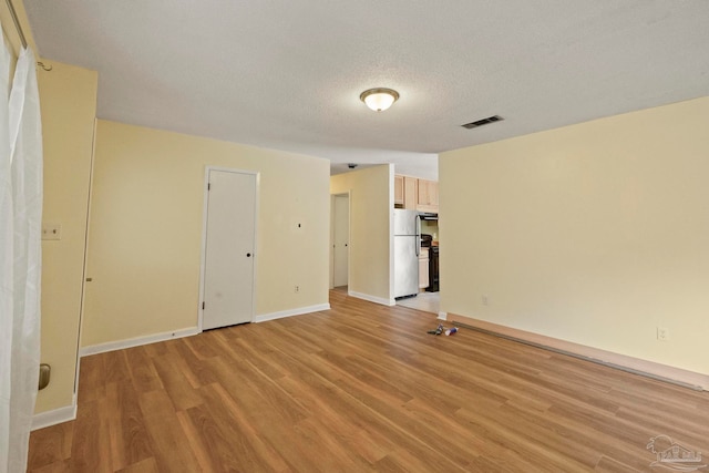 unfurnished room featuring a textured ceiling and light hardwood / wood-style flooring