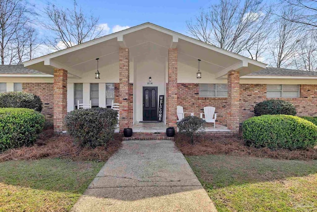 view of front facade featuring stucco siding, brick siding, and covered porch