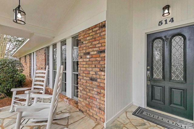 property entrance featuring covered porch and brick siding