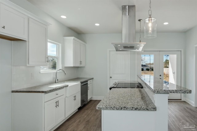 kitchen with hanging light fixtures, hardwood / wood-style floors, island exhaust hood, a center island, and light stone countertops