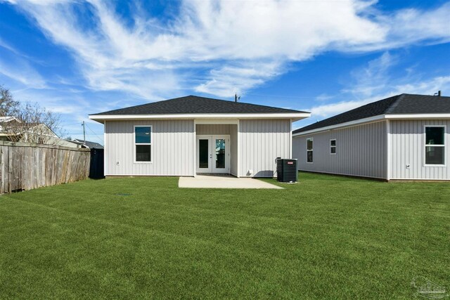 rear view of property featuring cooling unit, french doors, a lawn, and a patio area