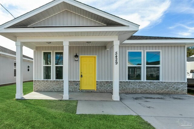 doorway to property featuring a yard and covered porch