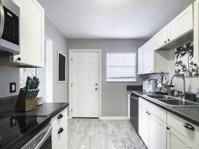 kitchen featuring appliances with stainless steel finishes, sink, light hardwood / wood-style flooring, and white cabinets