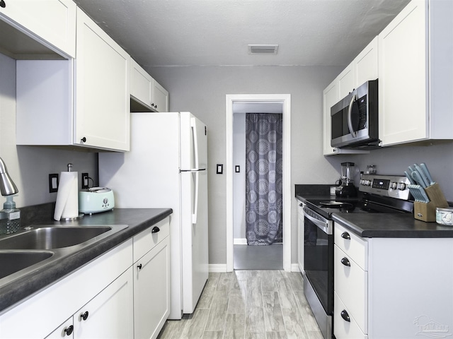 kitchen with sink, appliances with stainless steel finishes, white cabinetry, a textured ceiling, and light wood-type flooring