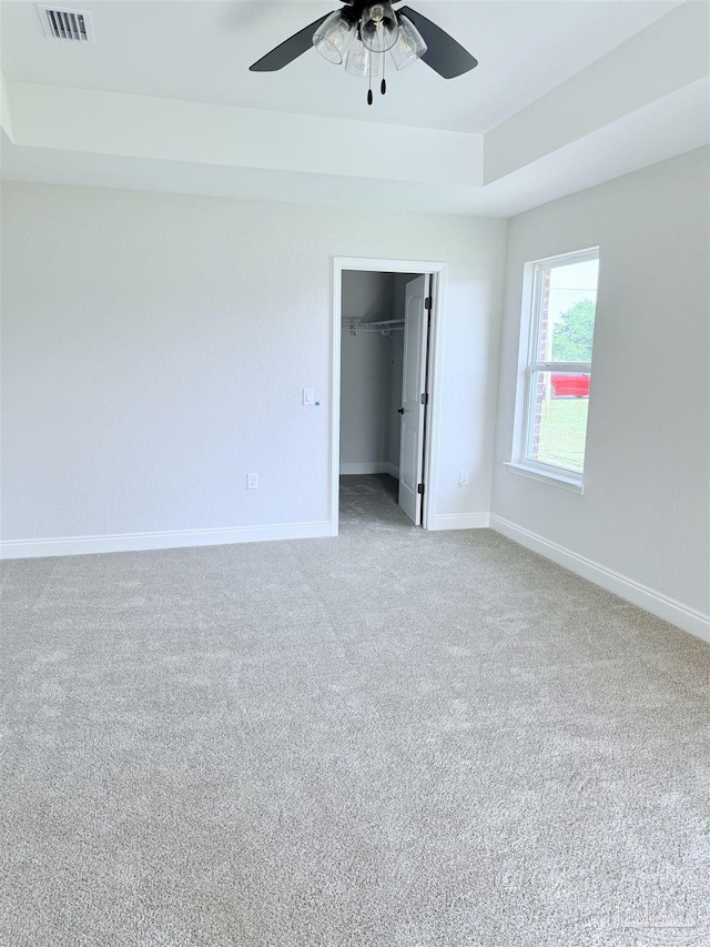 7919 Twin Lake Dr, Milton, FL 32583 - unfurnished bedroom featuring light colored carpet, baseboards, a tray ceiling, a walk in closet, and ceiling fan