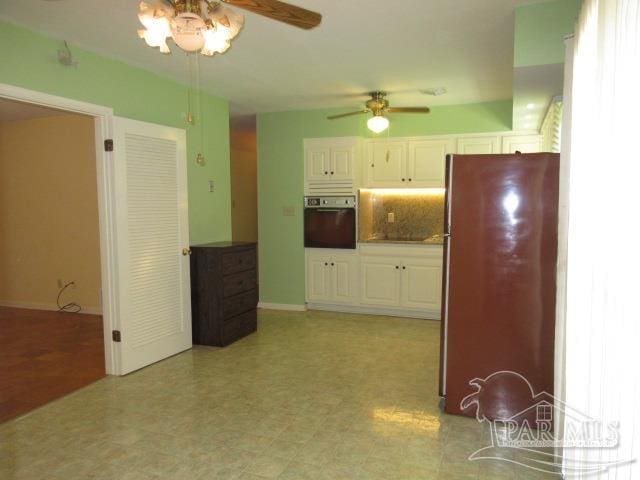 kitchen featuring oven, white cabinets, ceiling fan, and stainless steel fridge