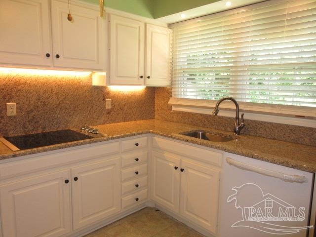 kitchen with white cabinets, black electric cooktop, stone counters, and sink