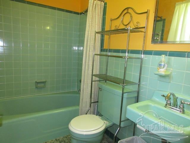 full bathroom with tile walls, sink, shower / tub combo, and toilet