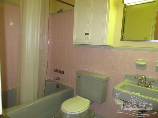 full bathroom featuring shower / tub combo, tile walls, toilet, and sink