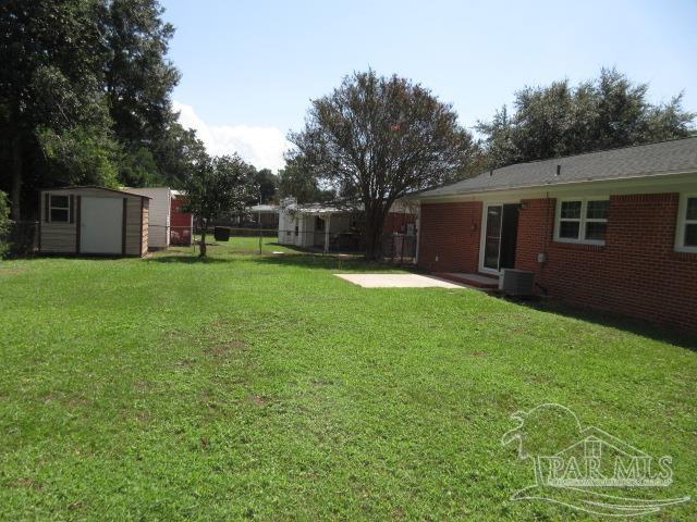 view of yard featuring cooling unit, a patio area, and a shed