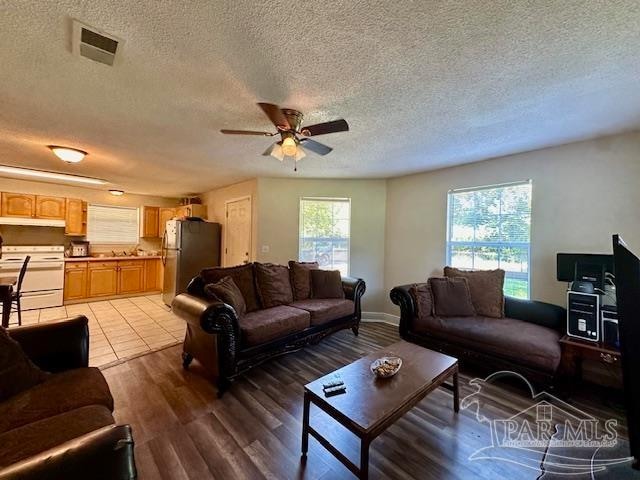 living room featuring ceiling fan, a textured ceiling, and light hardwood / wood-style flooring