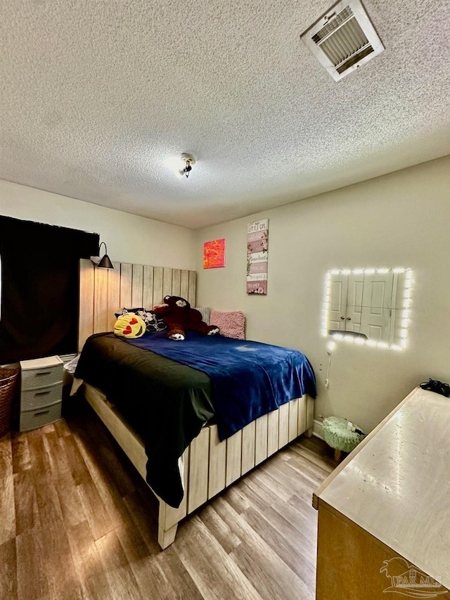 bedroom with a textured ceiling and light wood-type flooring