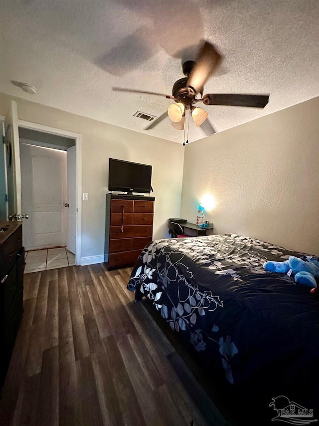 bedroom with hardwood / wood-style floors, a textured ceiling, and ceiling fan