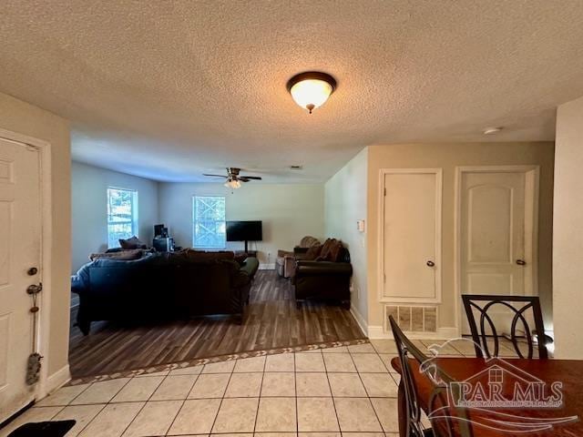 tiled living room featuring a textured ceiling and ceiling fan