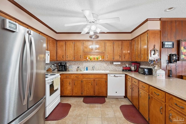 kitchen featuring a textured ceiling, sink, white appliances, and ornamental molding