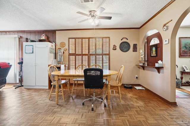 dining room featuring a textured ceiling, light parquet flooring, ceiling fan, and ornamental molding