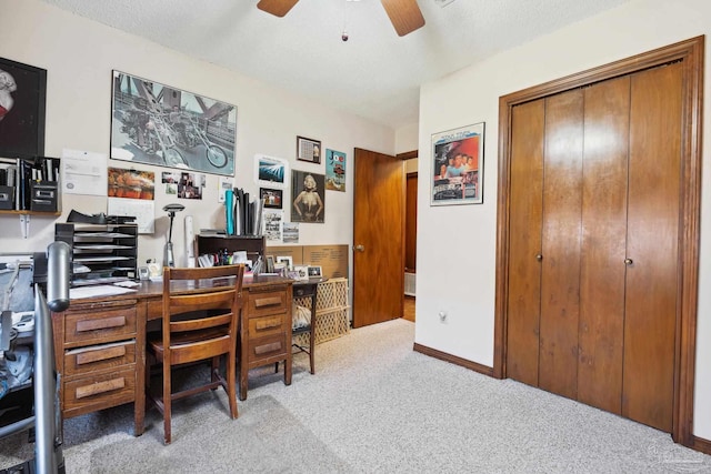 office area with a textured ceiling, ceiling fan, and light carpet