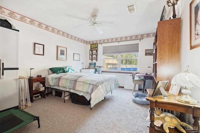 bedroom featuring ceiling fan, light colored carpet, and a textured ceiling