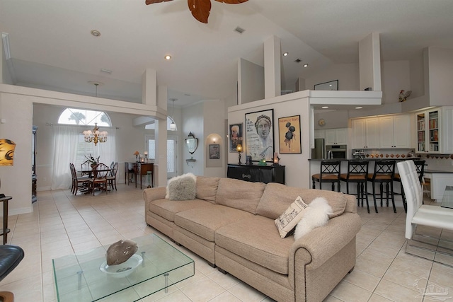 living room featuring high vaulted ceiling, light tile patterned floors, and ceiling fan with notable chandelier