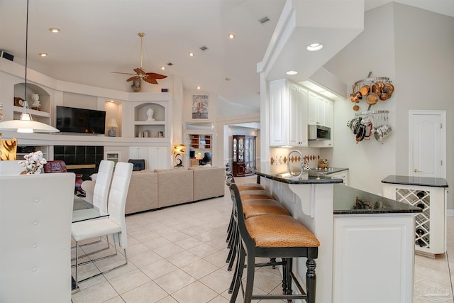 kitchen featuring built in features, light tile patterned floors, a kitchen breakfast bar, white cabinets, and ceiling fan