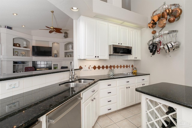 kitchen featuring stainless steel appliances, white cabinetry, sink, light tile patterned floors, and backsplash