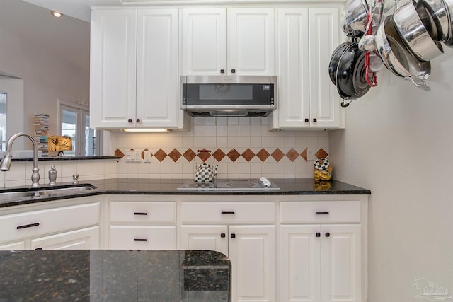 kitchen featuring stainless steel appliances, dark stone counters, sink, tasteful backsplash, and white cabinetry