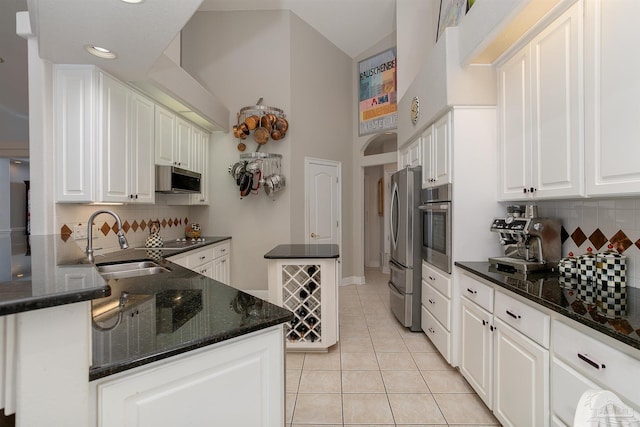 kitchen featuring decorative backsplash, sink, light tile patterned flooring, white cabinetry, and appliances with stainless steel finishes