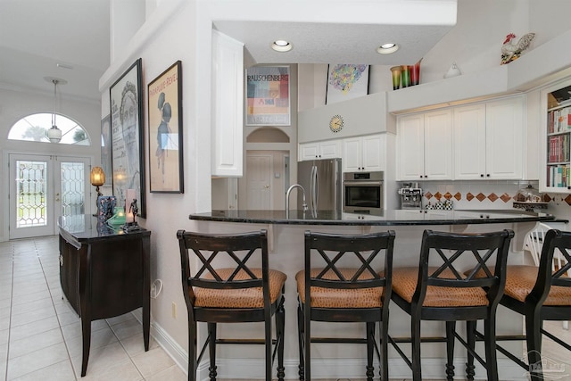 kitchen featuring kitchen peninsula, a breakfast bar area, light tile patterned flooring, and stainless steel appliances