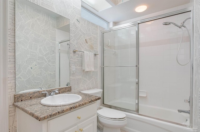 full bathroom featuring toilet, vanity, and shower / bath combination with glass door