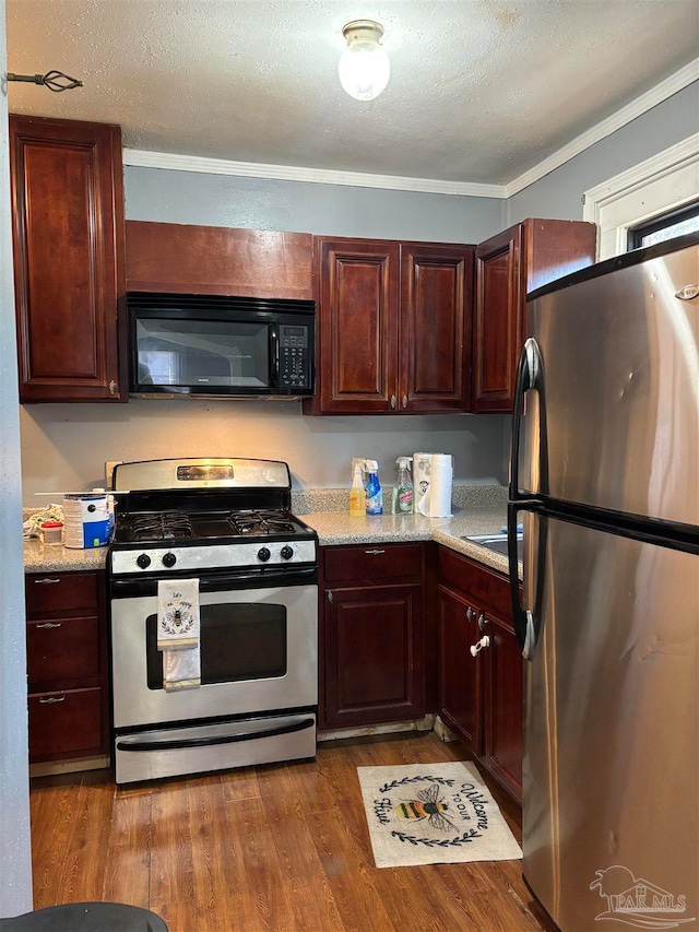 kitchen featuring dark wood-type flooring, crown molding, a textured ceiling, appliances with stainless steel finishes, and light stone counters