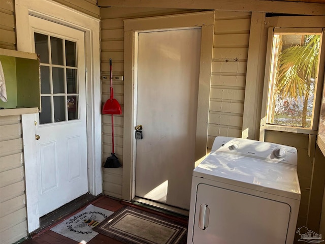 clothes washing area featuring wooden walls and washer / clothes dryer