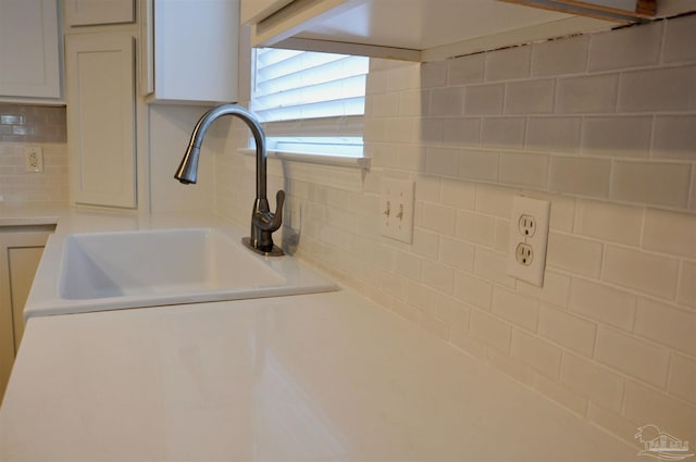 details with light countertops, tasteful backsplash, a sink, and white cabinetry