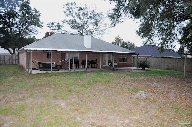 back of house featuring a lawn and a patio