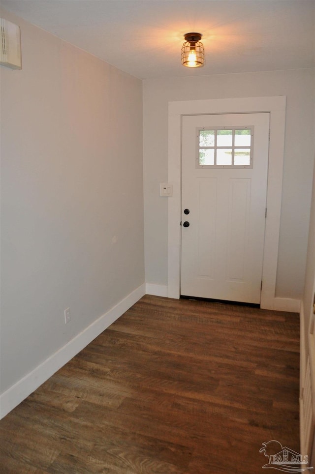 doorway with baseboards and dark wood-type flooring