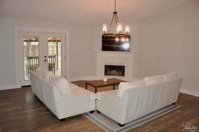 living room with a fireplace, dark hardwood / wood-style flooring, french doors, and a notable chandelier