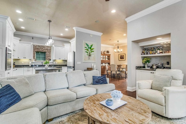 living room with hardwood / wood-style flooring, ornamental molding, and a chandelier