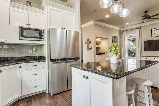 kitchen with crown molding, dark wood-type flooring, white cabinetry, hanging light fixtures, and stainless steel appliances