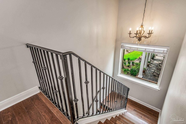 stairs with hardwood / wood-style floors and an inviting chandelier