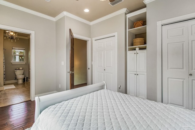 bedroom with crown molding, a chandelier, two closets, and dark hardwood / wood-style flooring